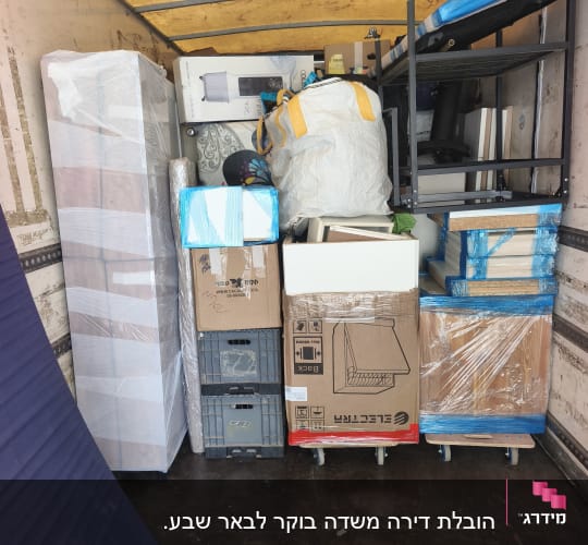 תא מטען של משאית הובלה עמוס ברהיטים עטופים וארגזים מסודרים
